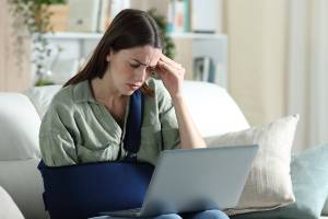 woman looking at laptop with arm in sling