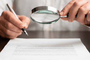Man going over paperwork with a magnifying glass