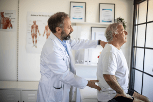 doctor examining older man's back