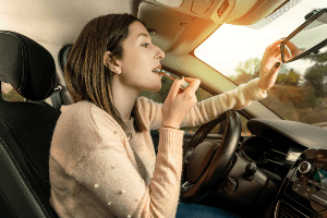 woman putting on her make-up in the car while driving.
