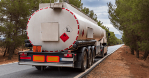 Truck carrying a gasoline tanker driving down a highway.