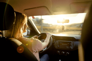 Woman driving with the sun glaring through the windshield. 