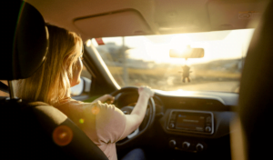 Woman driving with the sun glaring through the windshield.