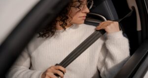 person putting on seat belt