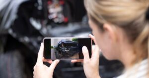 young blonde woman taking a cellphone pic of vehicle damage