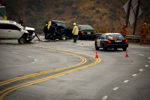 A car crash scene with multiple wreck vehicles and emergency personnel. 