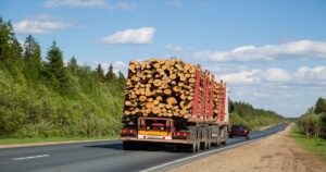 A truck with log cargo going down the street.