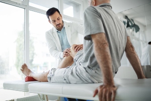 Healthcare professional examining someone's knee.