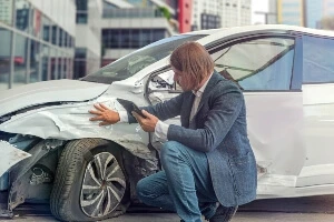 A man looking at the damage to the side of his car.