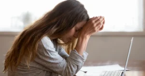 A woman stressed looking over her laptop.