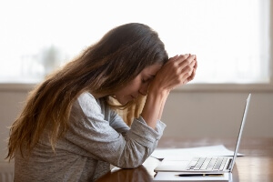 A woman stressed looking over her laptop.