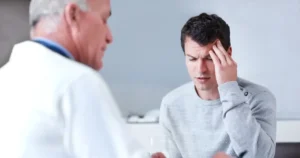 A man consulting with a medical professional while holding his head.