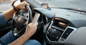 close-up of drivers = one hand on wheel, the other texting