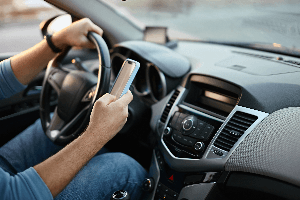 close-up of drivers = one hand on wheel, the other texting